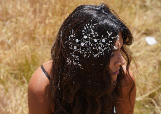 A model with dark hair wearing the Amelia headpiece, an accessory crafted with a blend of silver Swarovski, white pearls, and clear crystals.