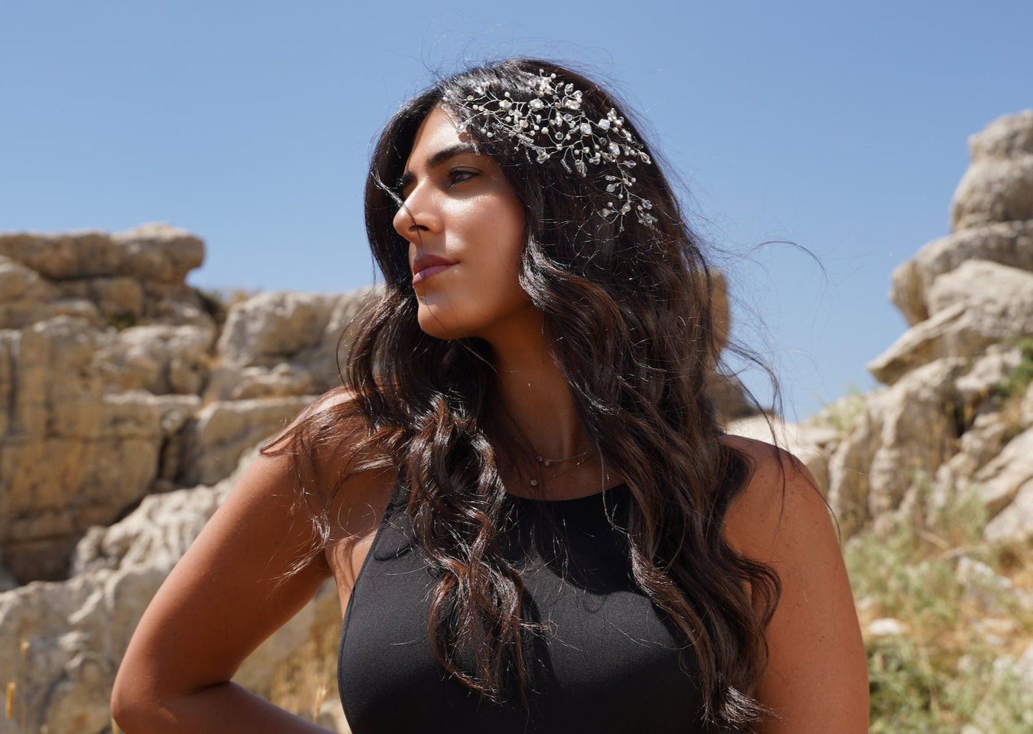 A model with dark hair wearing the Amelia headpiece, an accessory crafted with a blend of silver Swarovski, white pearls, and clear crystals.